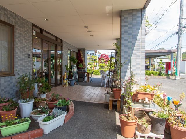 エントランスの植物とシート 玄関前 植物に囲まれた柔らかな雰囲気のエントランスです。待合でゆったりとした時間を過ごすことができます。
