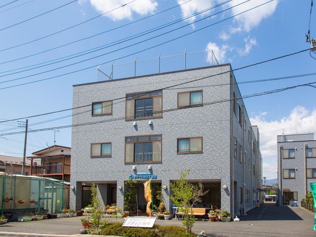 青空と建物の外観 外観  開放的な青空の下、清潔感がある建物の前には植物が並び、穏やかな環境が広がっています。住宅街の中にあり、地域に溶け込むデザインです。