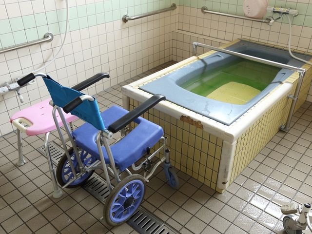 浴室の車椅子と浴槽 浴室 手すり付きの清潔感ある浴室です。車椅子からスムーズに移動可能な設計になっており、安心してご利用いただけます。