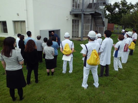 屋外で見学する職員たち  