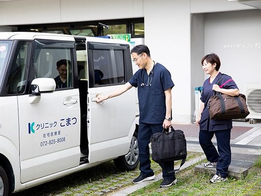 送迎車の前の職員  