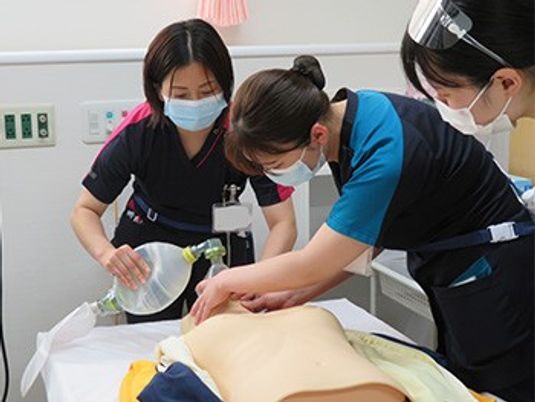 介護研修の人形と3人の職員  