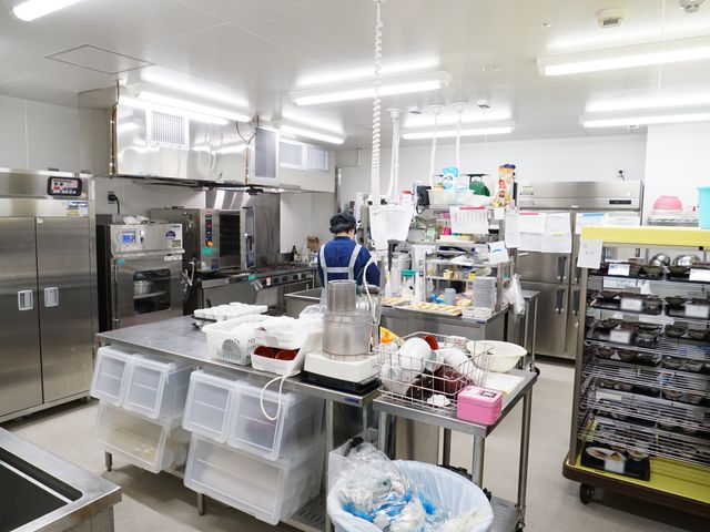 機能的なキッチン 厨房 清潔で整然とした配置の厨房です。調理スタッフが食事の準備に勤しむ姿が見受けられ、気配りが行き届いた環境を伺えます。