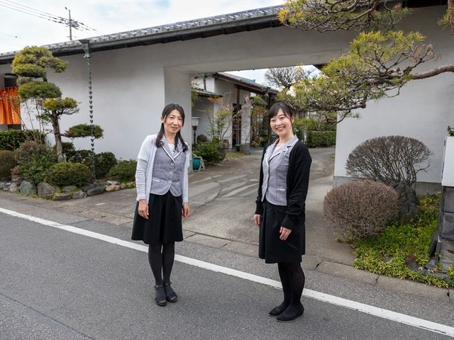 スタッフが並ぶ門前 外観   和風の門の前にスタッフが2人立っています。落ち着いたたたずまいで、訪れる方を迎える雰囲気が伝わります。
