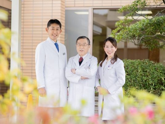 白衣の職員3人が並ぶ外観  
