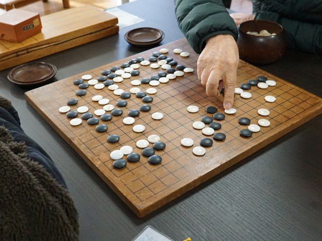 囲碁を打つ手と碁盤 レクリエーション じっくりと思考を巡らせる囲碁の時間。他の利用者とのコミュニケーションも充実しています。