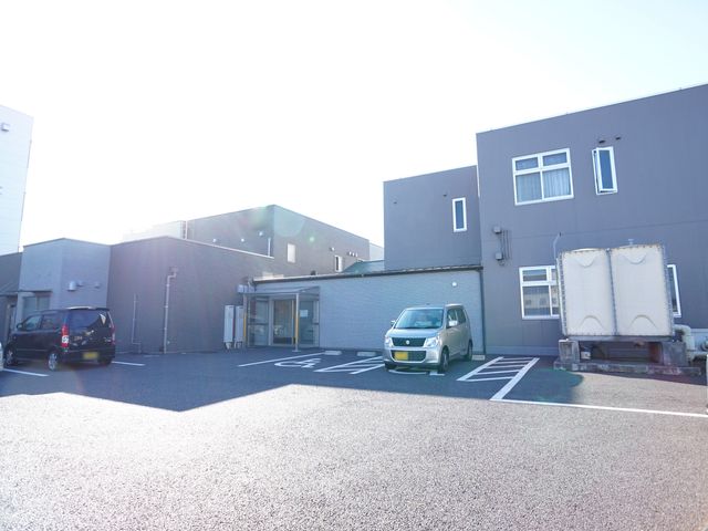 施設外観の明るい日差し 外観 ゆとりのある駐車スペースを備えた、清潔感のある建物です。明るい日差しと充実した設備が見込める環境でお仕事ができます。