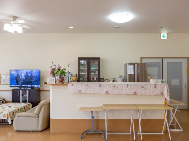 共有スペースの居心地の良い一角 キッチンカウンター ゆったりとしたソファが配置され、テレビでのくつろぎ時間を提供するアットホームなラウンジです。利用者様の憩いの場となっており、就業していただく方には温かい雰囲気を提供できる環境です。
