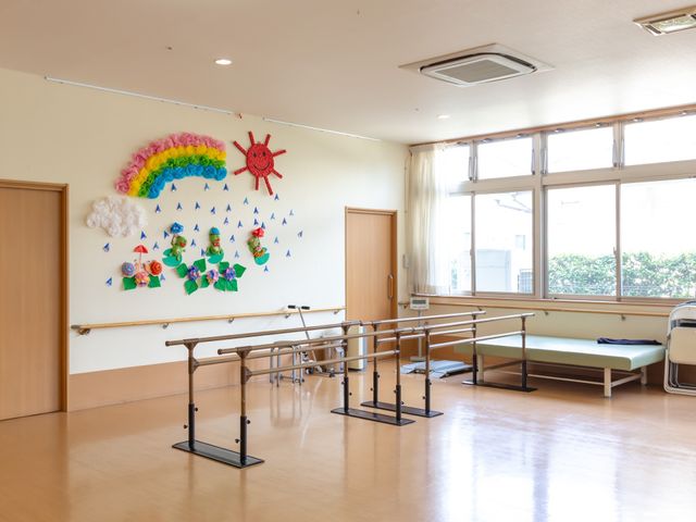 機能訓練室の明るい空間 リハビリスペース 広々とした機能訓練室では、リハビリテーションを取り入れた生活に寄与します。壁に飾られた手作りの装飾が温かみを与えています。