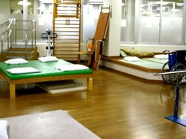 機能訓練室の様子 機能訓練室   木目調の床に運動器具が置かれ、明るく広めの空間です。訓練や体操の場として使いやすそうです。
