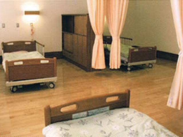 プライバシーに配慮した居室 居室 カーテンで仕切られた空間は、個々のプライバシーを大切にしています。床は温かみのある木材を使用しています。