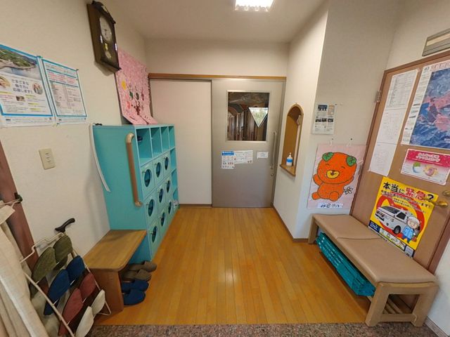明るい廊下と張り紙 廊下 明るい照明の下、ベンチや掲示物があり、穏やかな雰囲気が漂っています。棚には整理された物が収納されています。