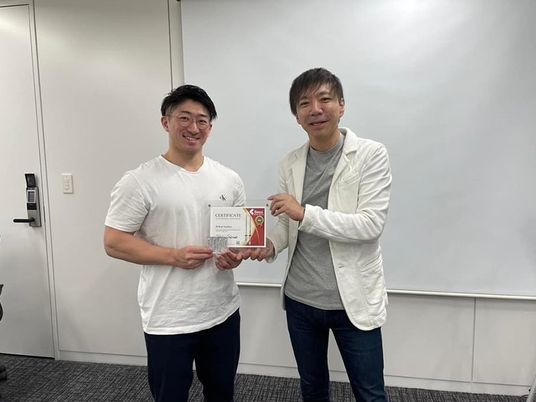 表彰状を持つ二人の室内  