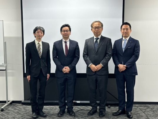 スーツ姿の男性4人が並ぶ会議室  