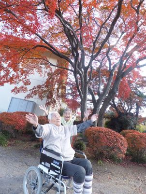 笑顔の利用者と彩り豊かな中庭
