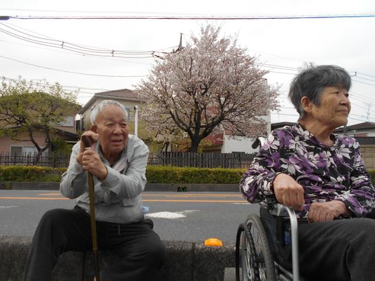 桜と共に外出する高齢者