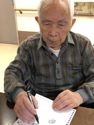 集中して物を書く高齢者