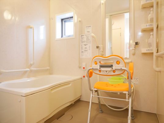 個浴用浴室には介護用椅子が１脚用意されている。可動式のシャワーヘッドが取り付けられている。シャンプーなどがある。