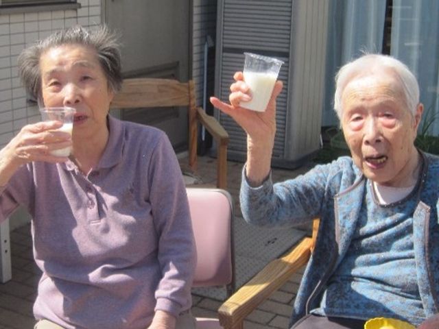 陽光の下でリラックスするお二人 日常 温かい日差しの中、テラスでお茶を楽しむお二人の様子。コミュニケーションも活発に行われており、心地よい時間が過ごせそうです。