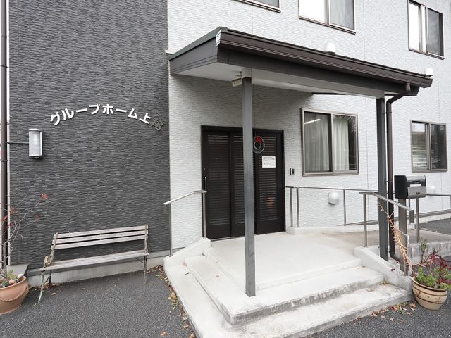 グレー壁のエントランス 外観 清潔感のあふれるエントランスです。ベンチがあり、一息つくスペースもしっかりと確保されています。