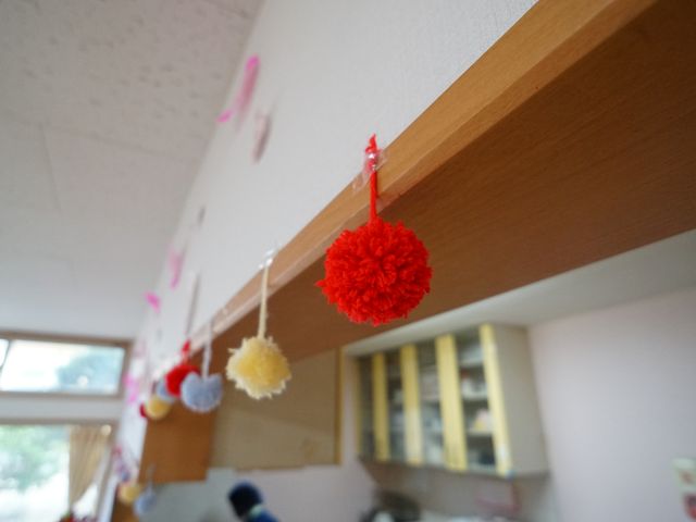 ポンポン飾り付け廊下 展示物 廊下には色とりどりの手作りポンポンが飾られており、訪れる人に温かい雰囲気を提供しています。