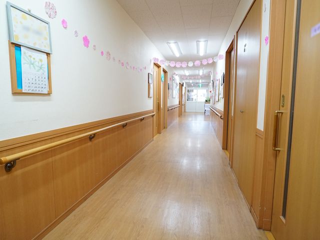 明るい廊下と掲示物 廊下 清潔感あふれる廊下は、壁に季節の飾りがあり、温かみのある雰囲気です。日々の業務でこのような安らぎの空間を提供できます。