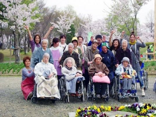 桜の花が咲き誇るスポットで、スタッフと入居者様が記念撮影をおこなっている。さまざまな四季イベントを開催している。