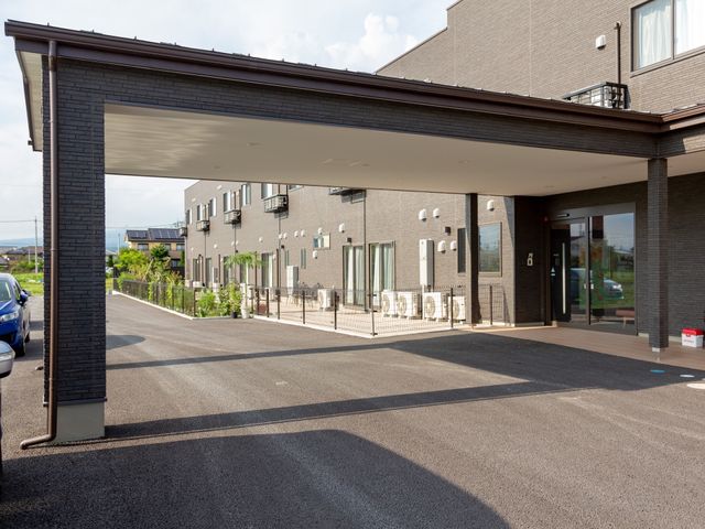 施設正面のエントランス風景 玄関 広々としたエントランスは、訪れる方々を明るい雰囲気でお迎えします。心地よい出勤が期待できる開放的な環境です。