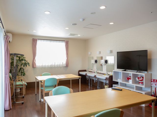 居室の様子 共有スペース 清潔感のある居室で、日光が差し込む窓の近くにはテーブルと椅子が配置されており、休息や様々な活動が行える空間です。