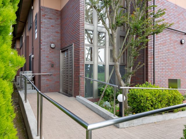 レンガ調のエントランス 外観 レンガの外壁が印象的なエントランスです。手すり沿いにアクセスできる設計で、誰もが安心して出入りができる環境が整っています。
