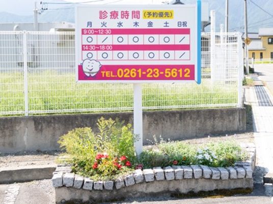 診療案内の看板と花壇の外観  