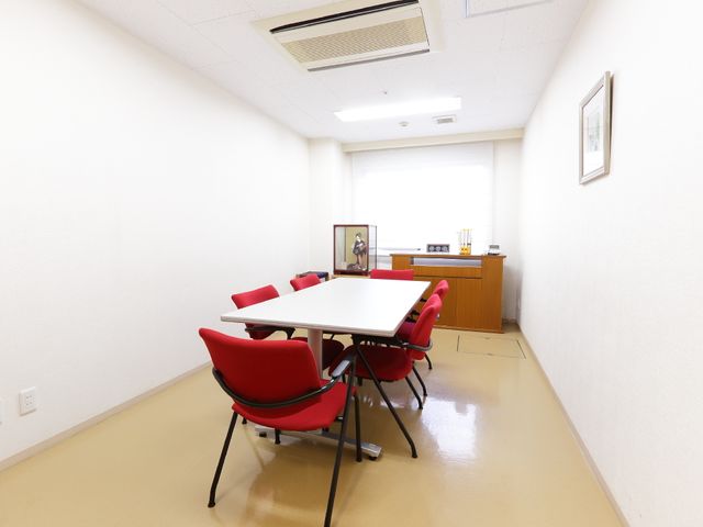 シンプルな多目的室 談話室 赤い椅子が並ぶ広々とした部屋は、様々な用途に対応可能です。採光が良く、静かで落ち着いた雰囲気です。