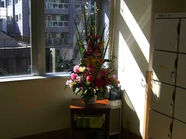 花飾りのある窓辺 廊下   窓から自然光が差し込み、花飾りが置かれた明るい廊下です。落ち着いた雰囲気で、働く場としても気持ちよさが感じられます。