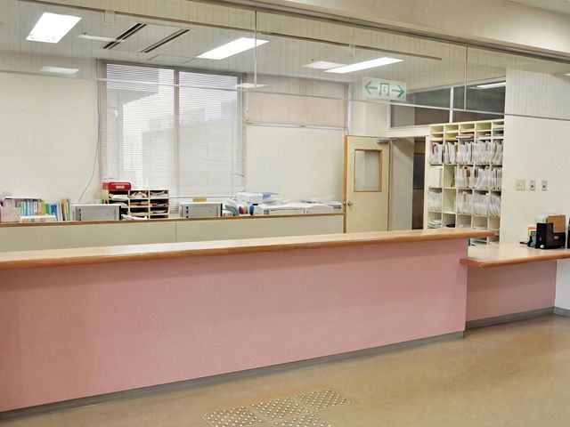 受付カウンターのあるロビー フロント   明るいロビーに広い受付カウンターがあり、書類棚や案内用の設備が整っています。来訪者対応のしやすさが感じられる空間です。