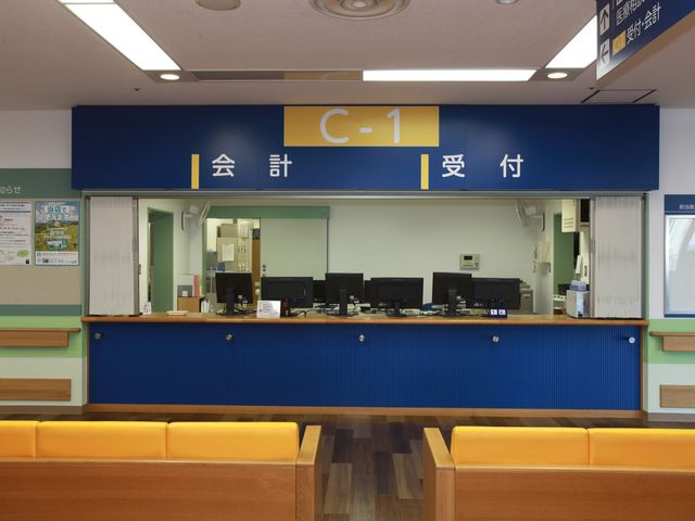 受付カウンター フロント   明るい受付カウンターがあり、複数のモニターが並んでいます。来訪時の案内や手続きの様子が伝わる、開放的な窓口です。