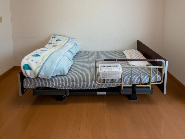 整った居室のベッド 居室 シンプルなデザインの居室は、清潔感があり、快適な休息をサポートします。機能的なベッド周りは、使いやすさに配慮されています。