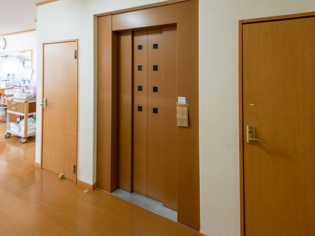 ゆとりある廊下のエレベーター エレベーター 移動が楽な広々としたエレベーターは、快適にお過ごしいただける設計です。ケアを必要とする方々もスムーズにご移動いただけます。