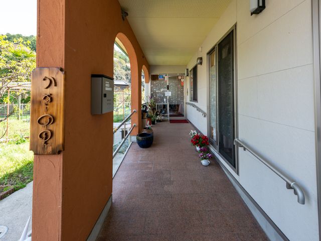 廊下の手すり付き通路 エントランス 手すりが設けられた通路は、安全にご移動いただける設計です。周囲に植えられた花が優しい雰囲気を演出しています。