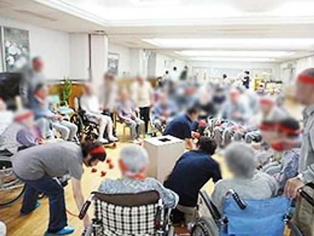 レクリエーションの様子 エントランス 広々としたスペースで、多くの人が集まり交流を楽しんでいます。楽しげな雰囲気です。