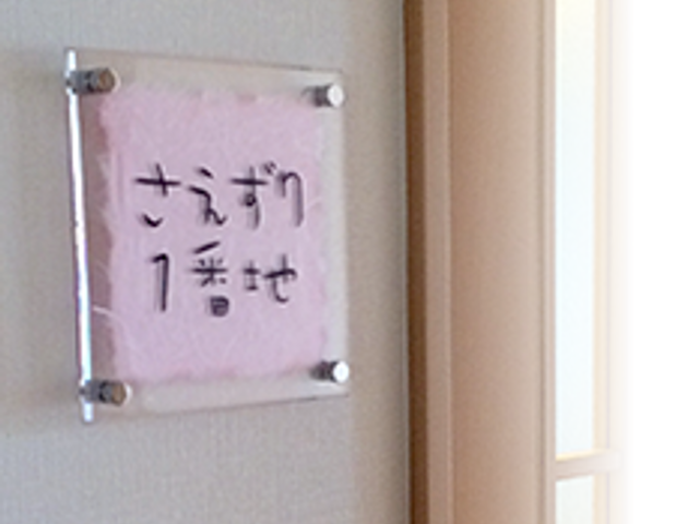 個室名を示す入口表示 居室 清潔感のある入口には、ご自身のスペースを示す名前表示があり、プライバシーが大切にされています。