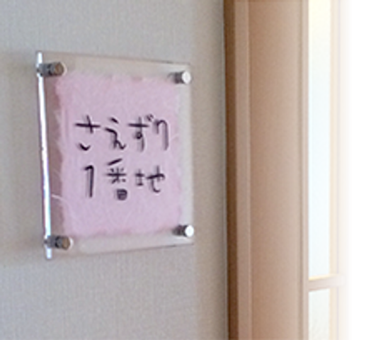 個室名を示す入口表示 居室 清潔感のある入口には、ご自身のスペースを示す名前表示があり、プライバシーが大切にされています。