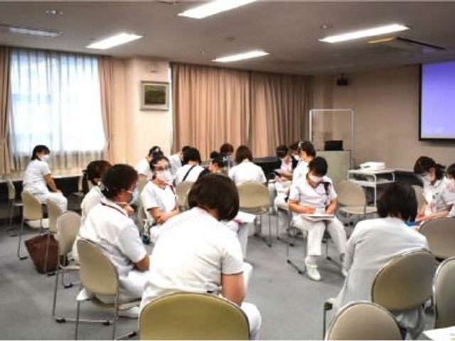 スタッフ研修室 多目的室   椅子を円形に並べた明るい多目的室で、複数のスタッフの方が集まっています。研修や打ち合わせなど、さまざまな使い方ができそうです。