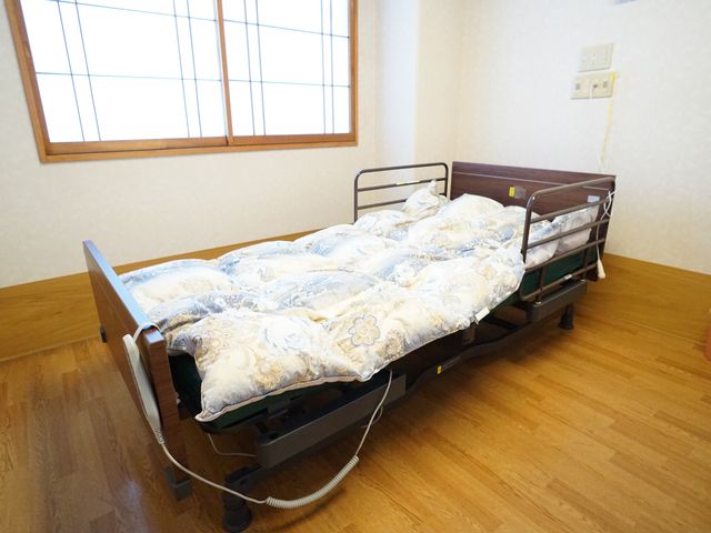 調整可能なベッドのある居室 居室 広々とした空間に配置された、機能的なベッドは安心して休息できる環境を提供します。温かみのある内装で、快適な私空間をお過ごしいただけます。