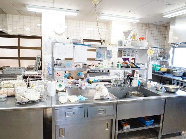 キッチンの作業風景 キッチン 清潔で整理されたキッチンで、スタッフが丁寧に調理を行っています。忙しない手つきで、美味しい食事を提供する準備が進められております。