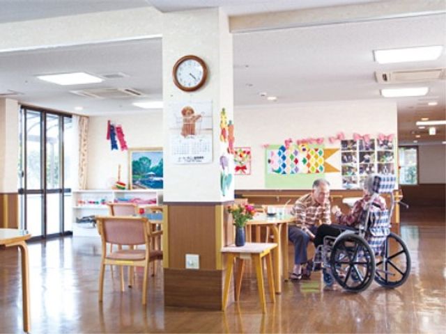 和やかな居室の様子 ロビー 窓際で心地よいひとときを過ごす二人の姿が微笑ましい共有スペースです。様々な工作品が飾られた明るく開放的な環境で皆様をお迎えします。