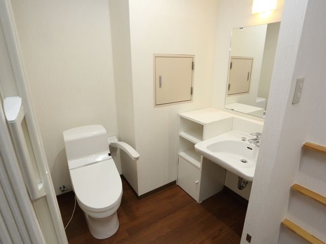 清潔なトイレと洗面台 トイレ 手すり付きで安全性を考慮したトイレスペースです。日々の暮らしに安心を提供する設計になっています。