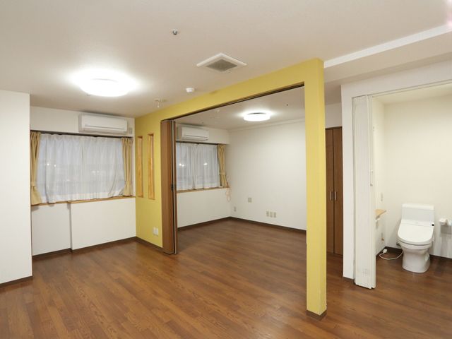 明るい居室のドアと洗面所 居室 ゆとりある広さの居室が確保されており、日々の生活がより快適に過ごせる工夫がされています。木目調のフローリングが温かみを感じさせる空間です。