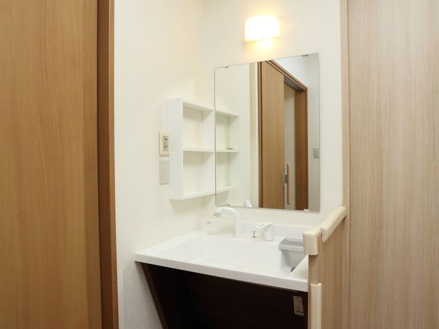 洗面台のあるシンプルな部屋 洗面台 洗面所には大きな鏡と収納棚があり、利便性を考慮した設計となっています。清潔感のあふれるこの空間で、毎日の身支度が快適に行えます。
