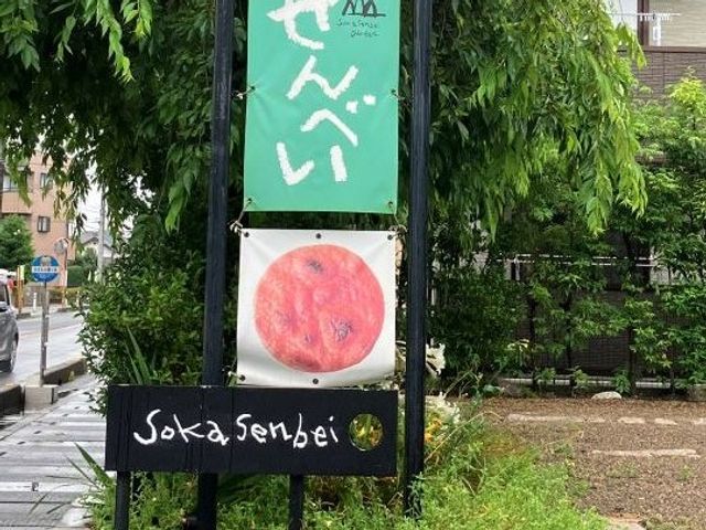 看板が立つ入口前の外観 外観   緑に囲まれた建物の前に看板が立っています。落ち着いた雰囲気で、働く前の印象を確認しやすいです。