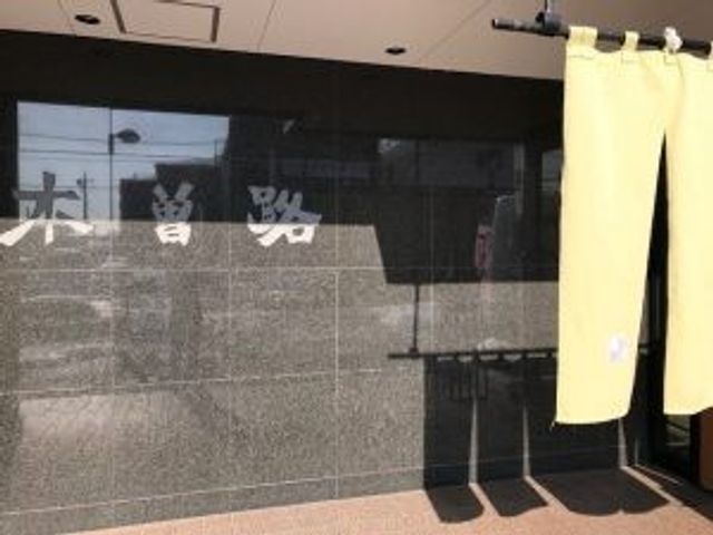 施設の看板前の外観 外観   黒い壁面に施設名が見える落ち着いた外観です。入口には暖簾がかかり、親しみやすい印象です。